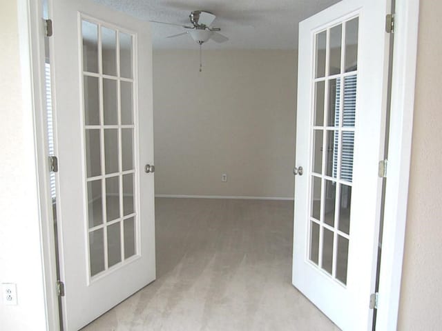 interior space with french doors, light carpet, ceiling fan, and a textured ceiling