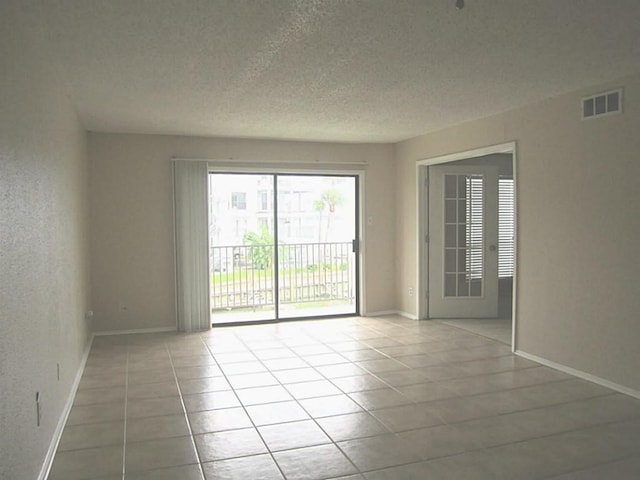 tiled spare room with a textured ceiling