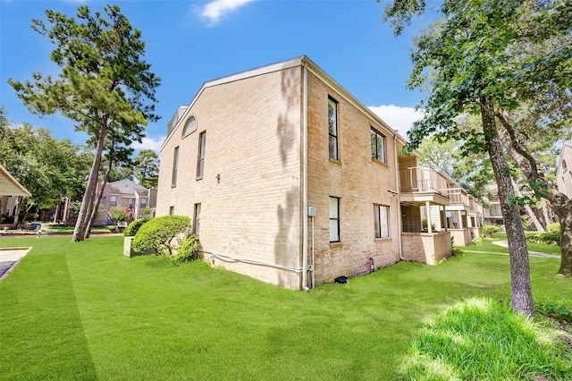 view of property exterior featuring a balcony and a lawn