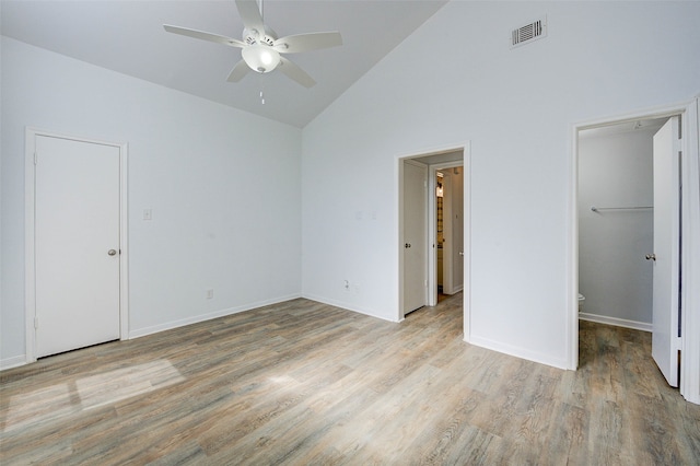 unfurnished bedroom with ceiling fan, light hardwood / wood-style flooring, a walk in closet, and high vaulted ceiling