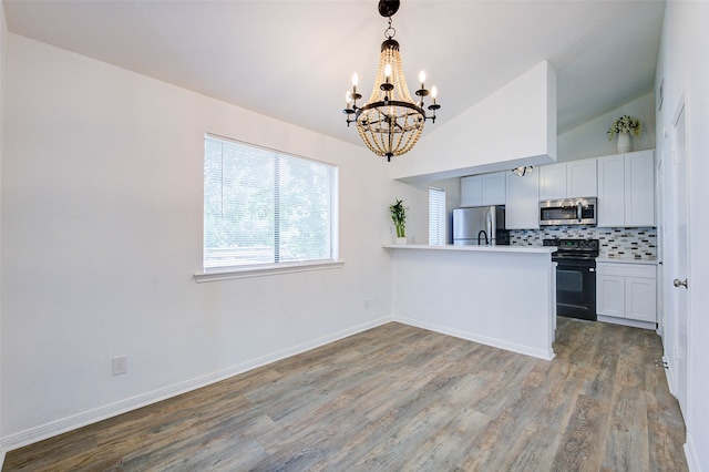 kitchen featuring decorative backsplash, kitchen peninsula, hardwood / wood-style floors, and stainless steel appliances