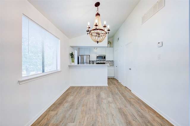 kitchen featuring a notable chandelier, tasteful backsplash, light wood-type flooring, appliances with stainless steel finishes, and kitchen peninsula