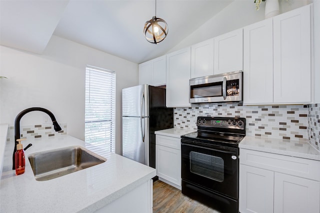 kitchen with plenty of natural light, sink, appliances with stainless steel finishes, and vaulted ceiling