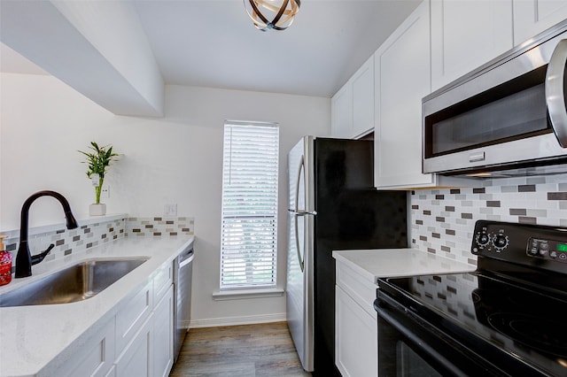 kitchen featuring stainless steel appliances, light wood-type flooring, backsplash, and sink