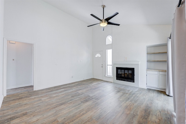 unfurnished living room featuring light hardwood / wood-style flooring, a tile fireplace, and ceiling fan