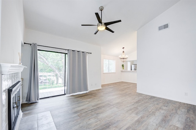 unfurnished living room with ceiling fan with notable chandelier, hardwood / wood-style flooring, and vaulted ceiling