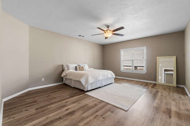 bedroom with ceiling fan, hardwood / wood-style floors, and a textured ceiling