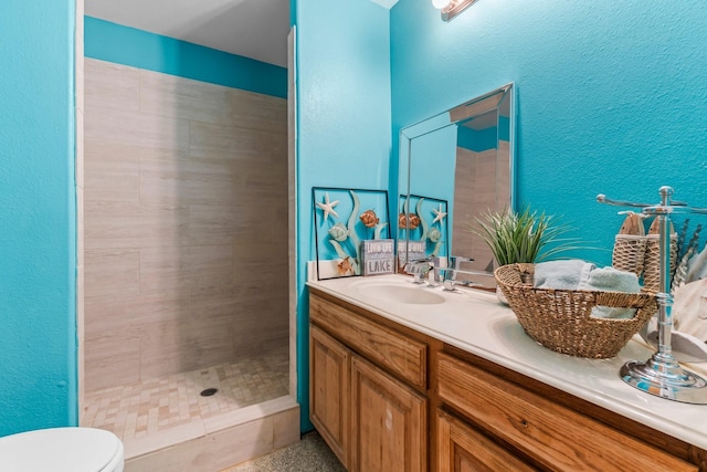 bathroom featuring vanity, toilet, and a tile shower