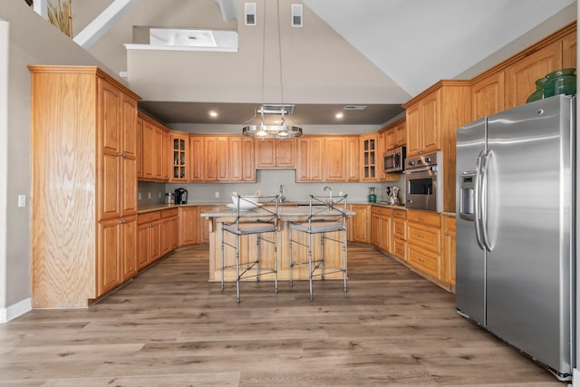 kitchen with light hardwood / wood-style floors, decorative light fixtures, stainless steel appliances, and a center island