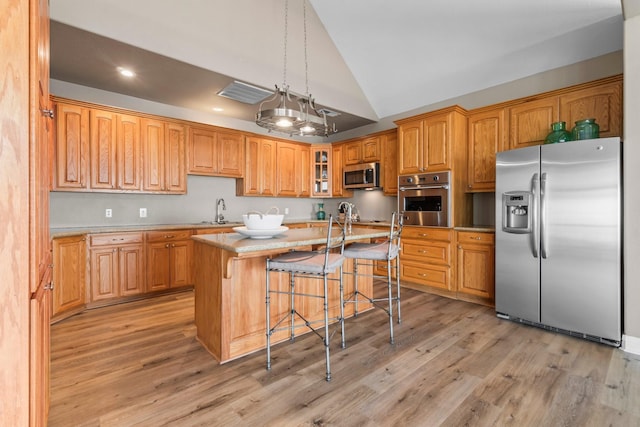 kitchen with a kitchen island, appliances with stainless steel finishes, a kitchen breakfast bar, and light hardwood / wood-style floors