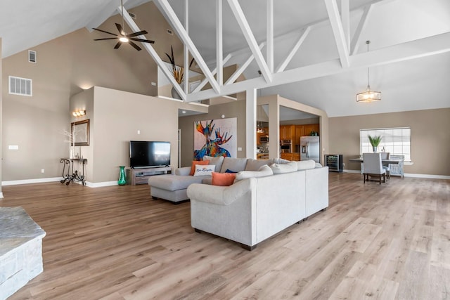 living room with vaulted ceiling, ceiling fan, and light wood-type flooring