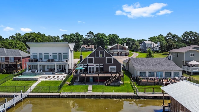 back of house with a yard, a pool side deck with water view, and a patio area