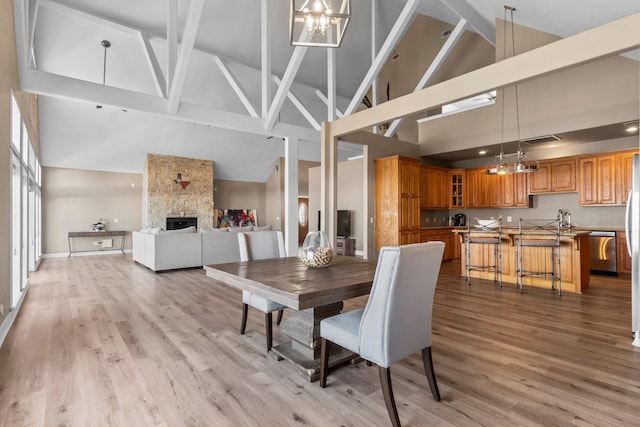 dining area with a fireplace, sink, light hardwood / wood-style flooring, and a notable chandelier