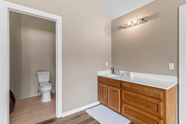 bathroom with hardwood / wood-style flooring, vanity, lofted ceiling, and toilet