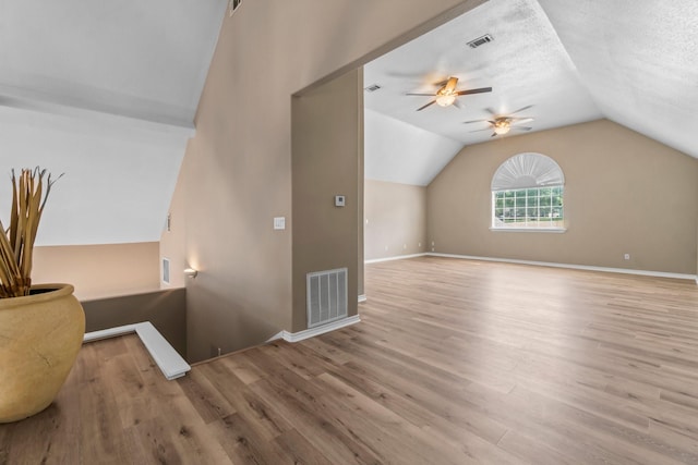 additional living space featuring ceiling fan, light hardwood / wood-style flooring, a textured ceiling, and vaulted ceiling