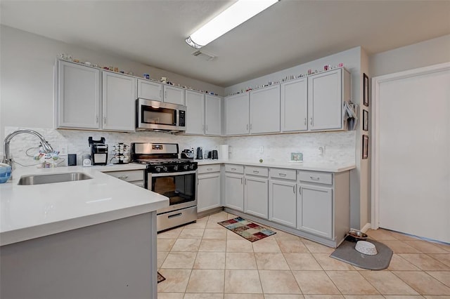 kitchen featuring tasteful backsplash, sink, light tile patterned flooring, and appliances with stainless steel finishes