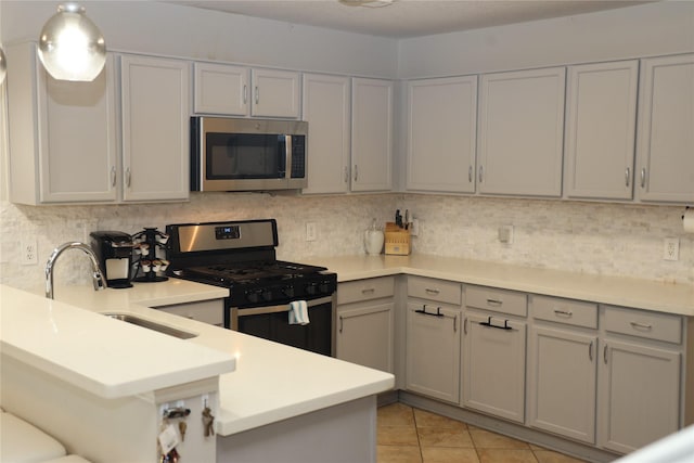 kitchen featuring kitchen peninsula, tasteful backsplash, stainless steel appliances, sink, and light tile patterned floors