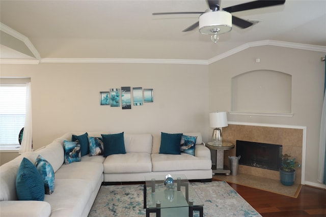 living room featuring a tile fireplace, ceiling fan, vaulted ceiling, hardwood / wood-style flooring, and ornamental molding