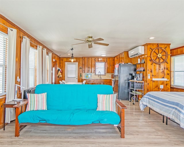 living area featuring ceiling fan, light wood-type flooring, wood walls, and a wall unit AC