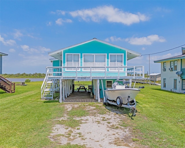 back of house with a yard, a deck with water view, and a carport