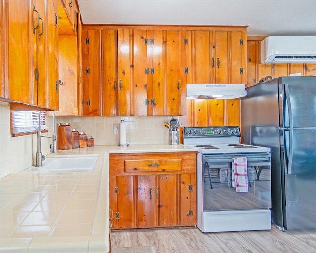 1214 County Road 201, Sargent, TX 77414 - kitchen featuring white electric range oven, freestanding refrigerator, under cabinet range hood, tile countertops, and brown cabinetry