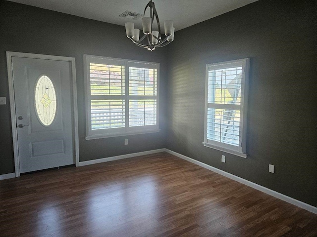 foyer with plenty of natural light, dark wood-type flooring, and a notable chandelier