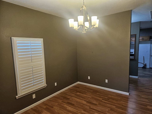 spare room featuring a notable chandelier and dark hardwood / wood-style floors