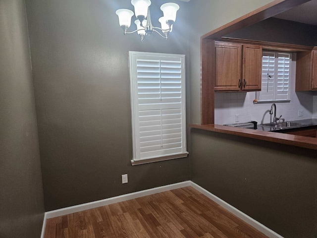 dining space featuring wood-type flooring, sink, and a chandelier