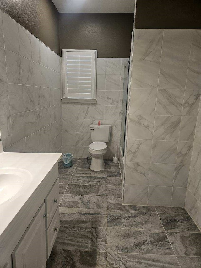 full bathroom featuring combined bath / shower with glass door, vanity, toilet, and tile walls