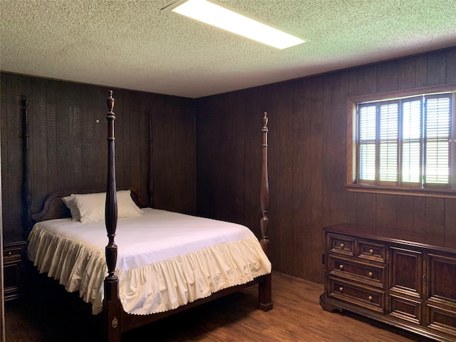 bedroom with wood-type flooring, a textured ceiling, and wooden walls