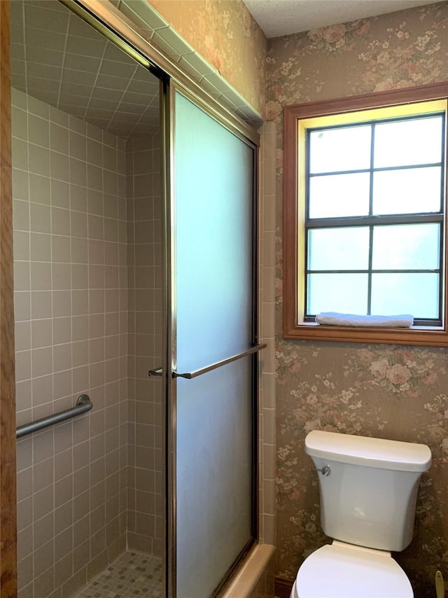 bathroom with a shower with door and toilet