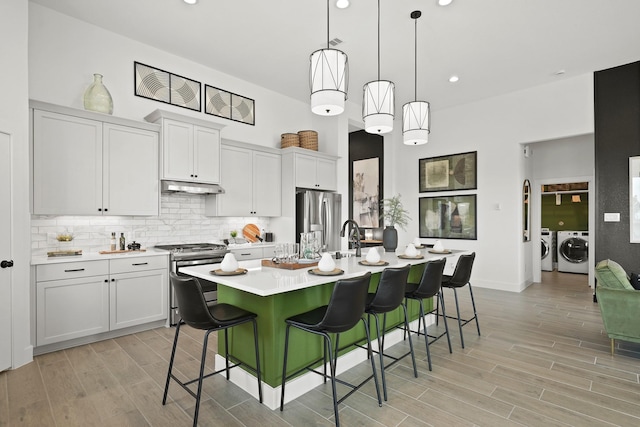 kitchen featuring appliances with stainless steel finishes, separate washer and dryer, white cabinetry, and pendant lighting