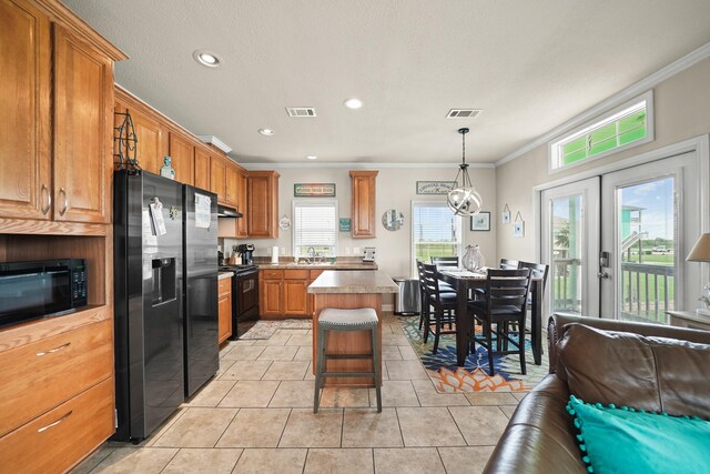 kitchen with light tile patterned flooring, a center island, a healthy amount of sunlight, and black appliances