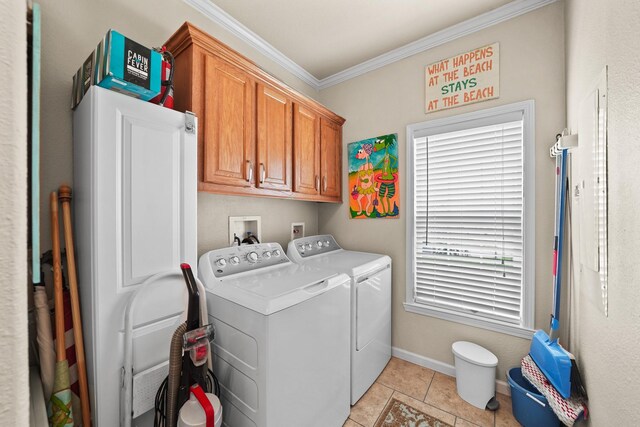 laundry room featuring washing machine and clothes dryer, cabinets, ornamental molding, and light tile patterned floors