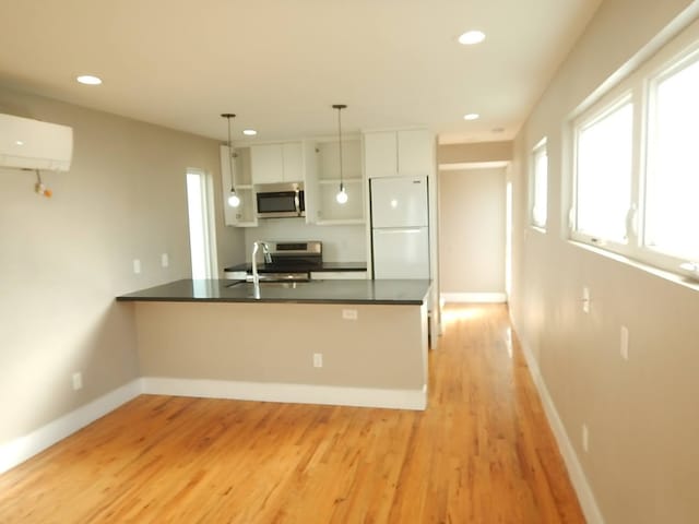 kitchen featuring white refrigerator, white cabinets, a wealth of natural light, and light wood-type flooring