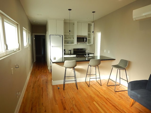 kitchen featuring light wood-type flooring, white cabinets, kitchen peninsula, range, and white fridge