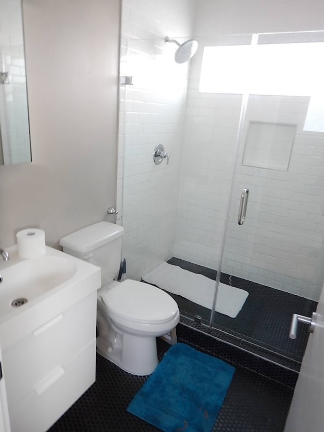 bathroom with tile floors, an enclosed shower, toilet, and vanity