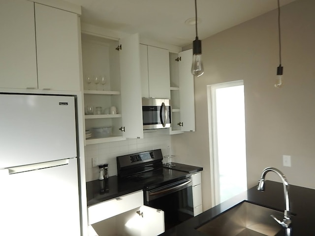 kitchen with appliances with stainless steel finishes, white cabinets, backsplash, pendant lighting, and sink