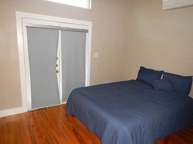 bedroom with a closet, dark hardwood / wood-style flooring, and a wall mounted air conditioner