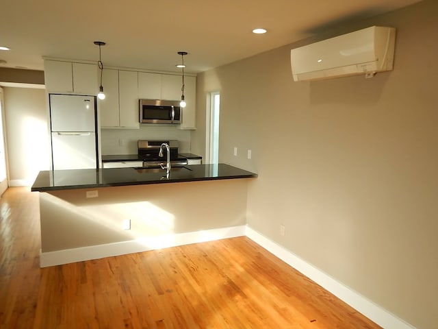 kitchen featuring light hardwood / wood-style floors, white refrigerator, kitchen peninsula, and a wall mounted air conditioner