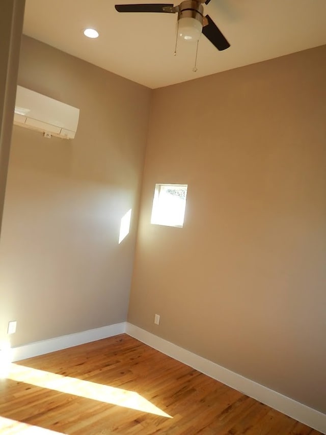 spare room with an AC wall unit, ceiling fan, and hardwood / wood-style floors