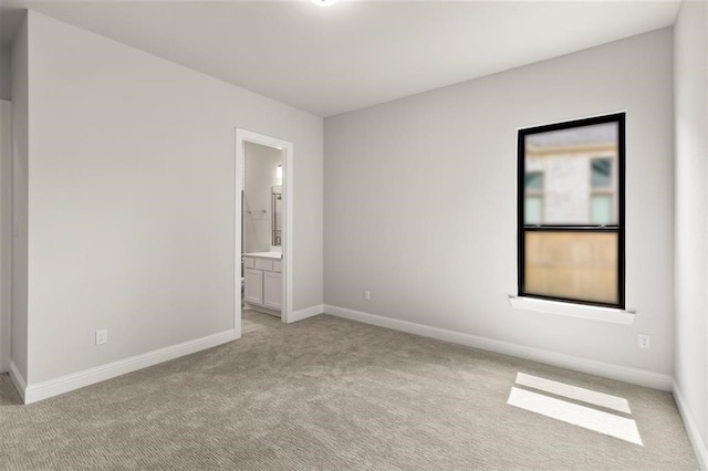 unfurnished bedroom featuring ensuite bath and light carpet