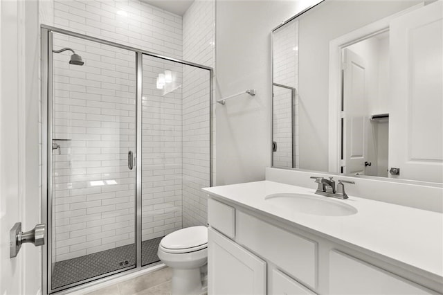 bathroom featuring tile patterned flooring, vanity, toilet, and walk in shower