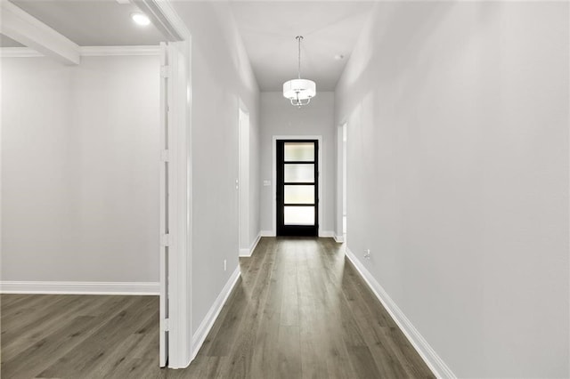 doorway with dark hardwood / wood-style flooring, ornamental molding, and an inviting chandelier