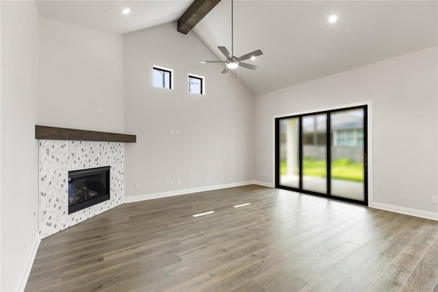 unfurnished living room with ceiling fan, beamed ceiling, high vaulted ceiling, hardwood / wood-style floors, and a fireplace