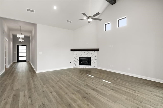 unfurnished living room with a fireplace, beam ceiling, ceiling fan with notable chandelier, and hardwood / wood-style floors