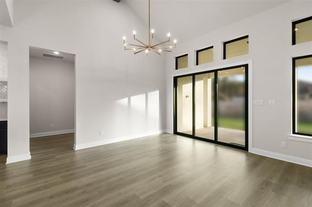 unfurnished room featuring high vaulted ceiling, hardwood / wood-style floors, and a chandelier