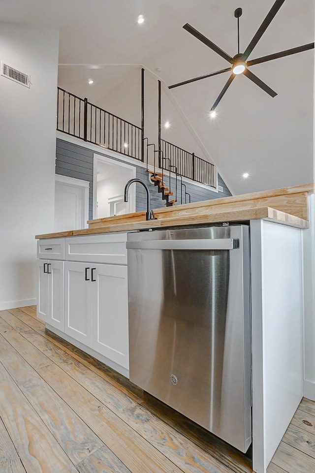 kitchen featuring stainless steel dishwasher, ceiling fan, high vaulted ceiling, white cabinets, and light hardwood / wood-style floors