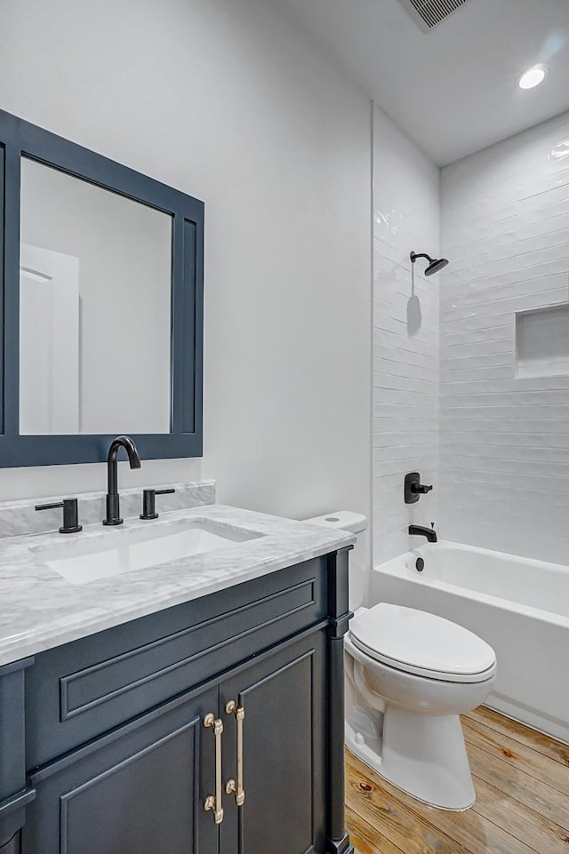 full bathroom featuring hardwood / wood-style floors, vanity, toilet, and tiled shower / bath