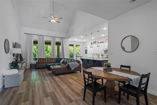 dining space featuring hardwood / wood-style flooring, high vaulted ceiling, ceiling fan, and sink